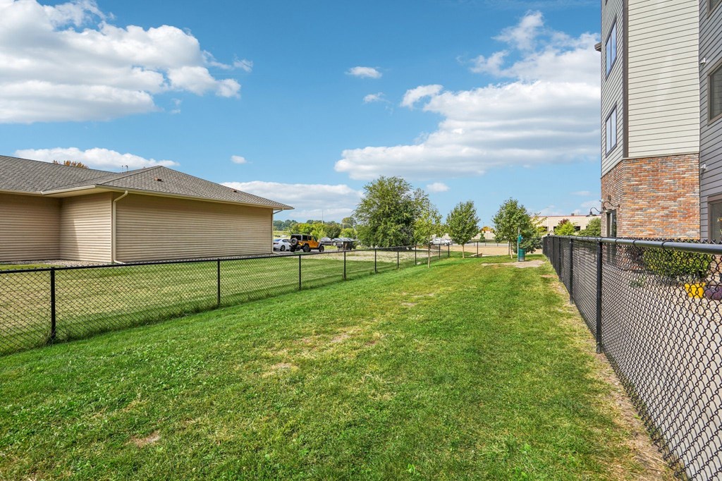 A backyard with a fence and a house in the background.