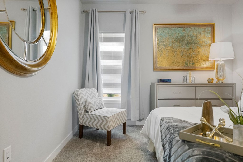A bedroom with a bed, chair, and a painting on the wall.