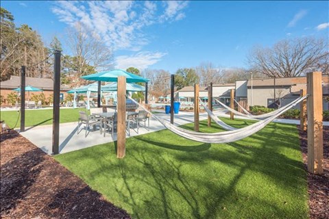 a playground with hammocks and tables and umbrellas