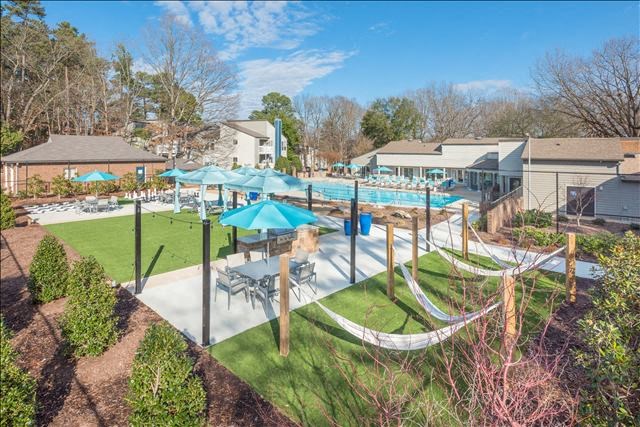 a backyard with hammocks and umbrellas and houses in the background