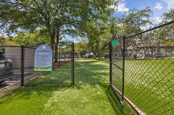 A sign is posted on a fence in a green area.