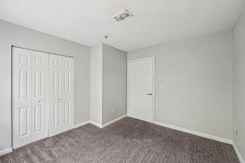 A room with a carpeted floor and a white door.