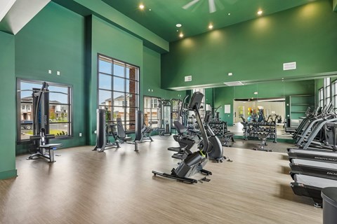 A gym with a variety of equipment including treadmills, weights, and exercise machines.