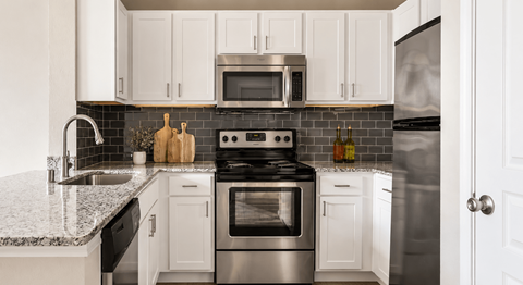 A modern kitchen with white cabinets and stainless steel appliances.