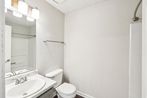 A white bathroom with a toilet, sink, and mirror.