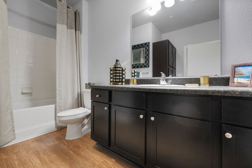 A bathroom with black cabinets and a white toilet.