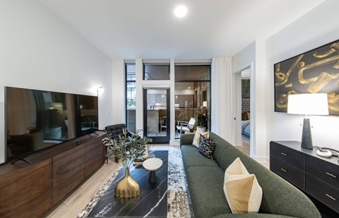 A modern living room with a green sofa and a gold vase.