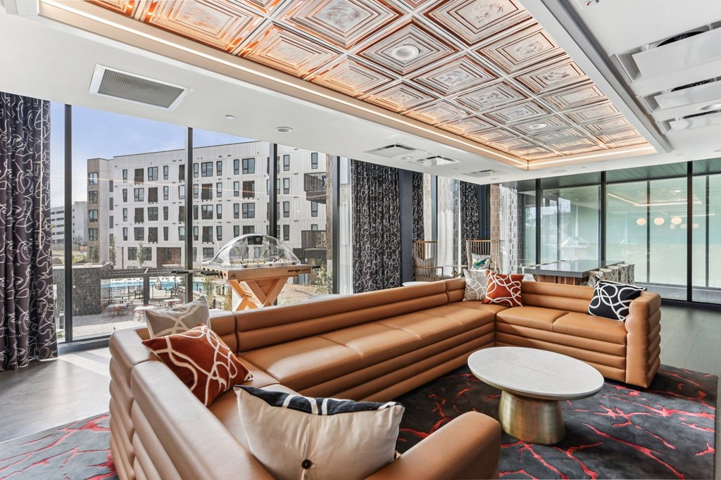 A living room with a large orange couch and a patterned rug.