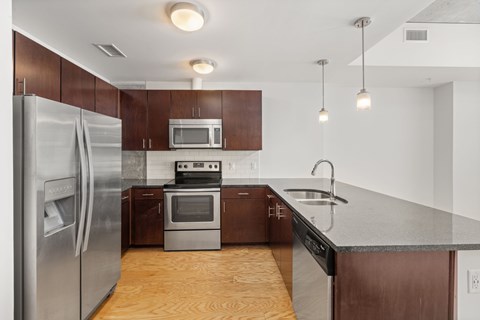 A modern kitchen with a stainless steel refrigerator and wooden cabinets.