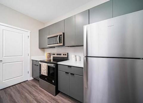 A kitchen with a stainless steel refrigerator and a black oven.