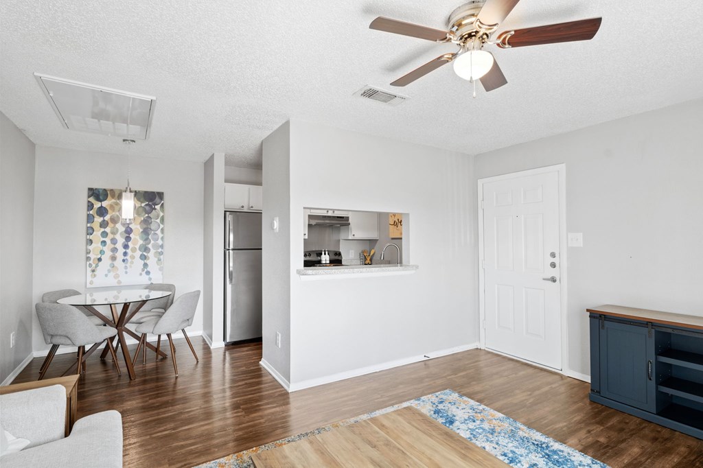 A room with a ceiling fan and a dining table with chairs.