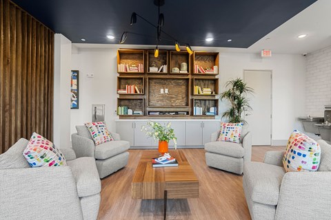 A living room with grey couches, a coffee table, and a bookshelf with books and decorative items.