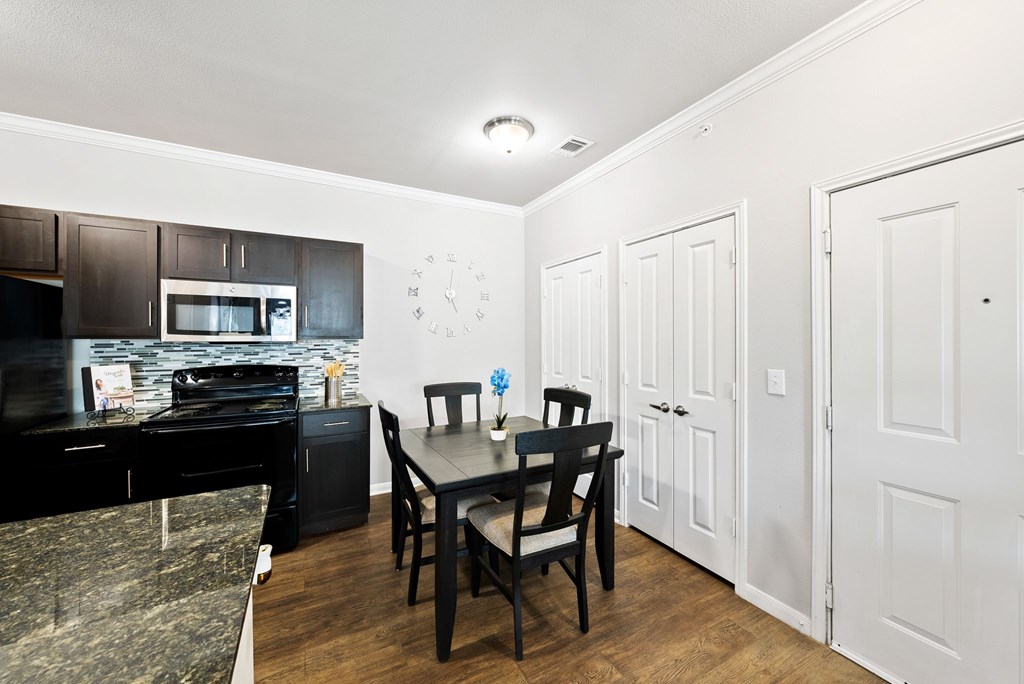 A black dining table with four chairs is in a white room.