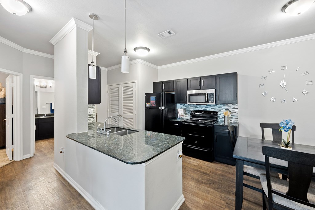 A kitchen with black cabinets and a granite countertop.
