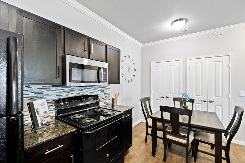 A kitchen with black cabinets and a black stove top oven.