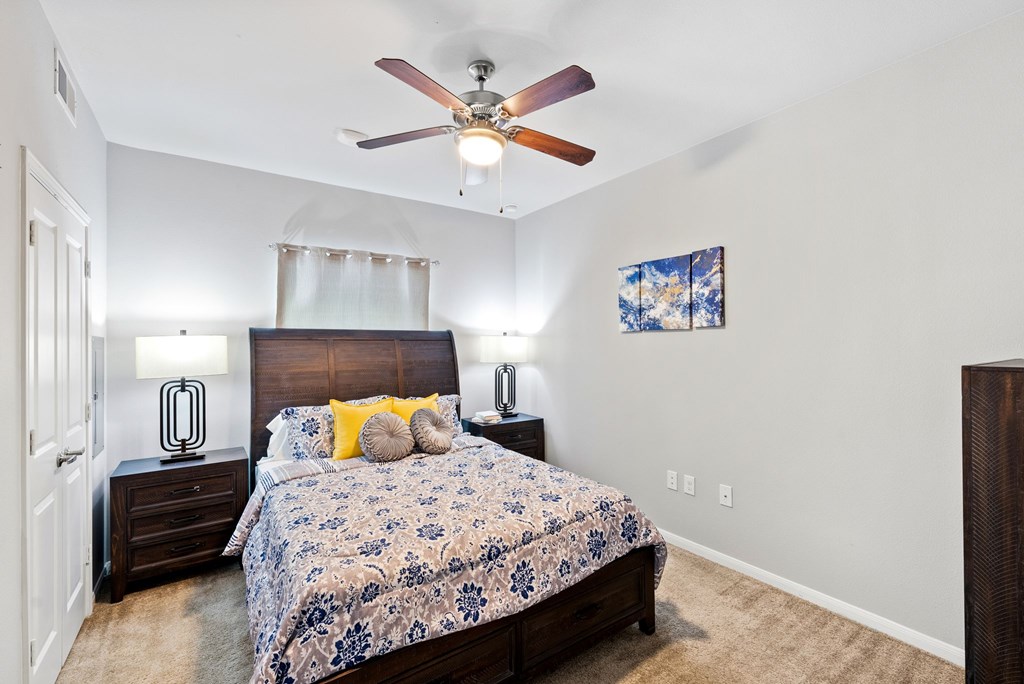 A bedroom with a bed, nightstands, and a ceiling fan.