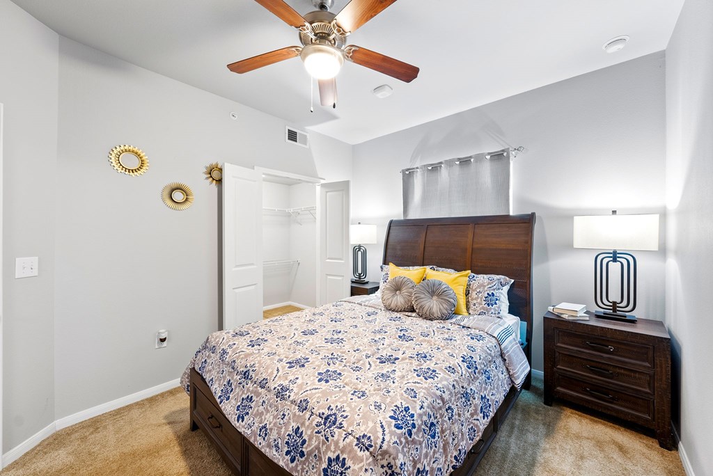 A bedroom with a bed, nightstand, and ceiling fan.