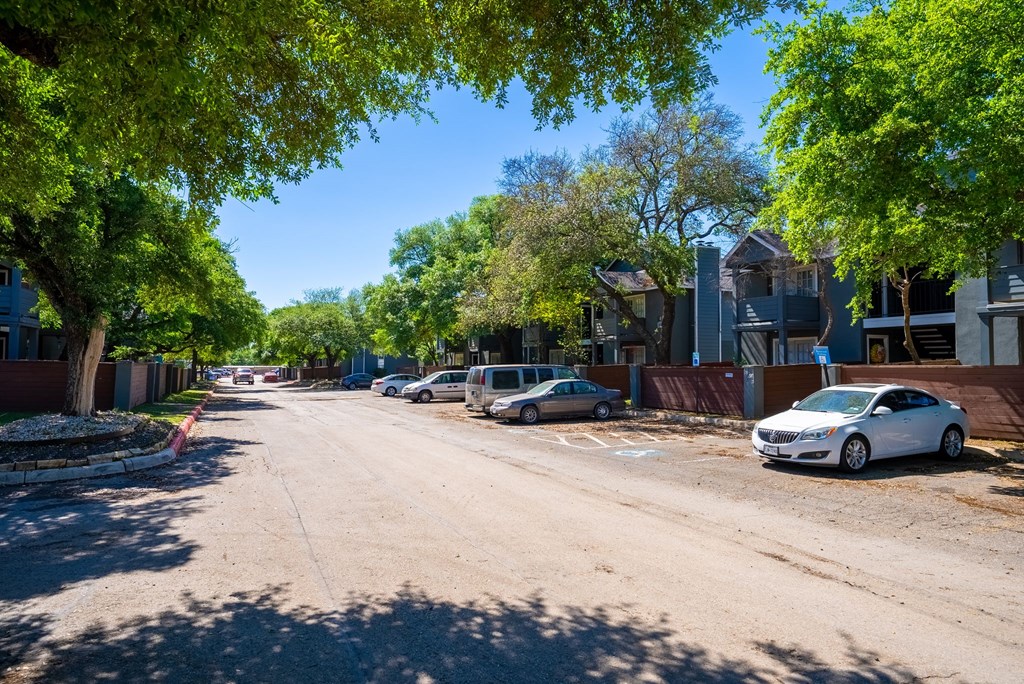A street with cars parked on the side and trees lining the road.