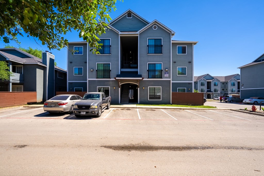 A parking lot in front of a multi-story apartment building.