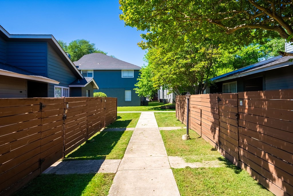 A sunny day in a residential area with houses and a sidewalk.