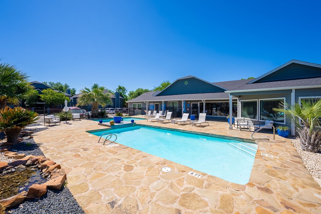 A large outdoor swimming pool surrounded by a stone border.