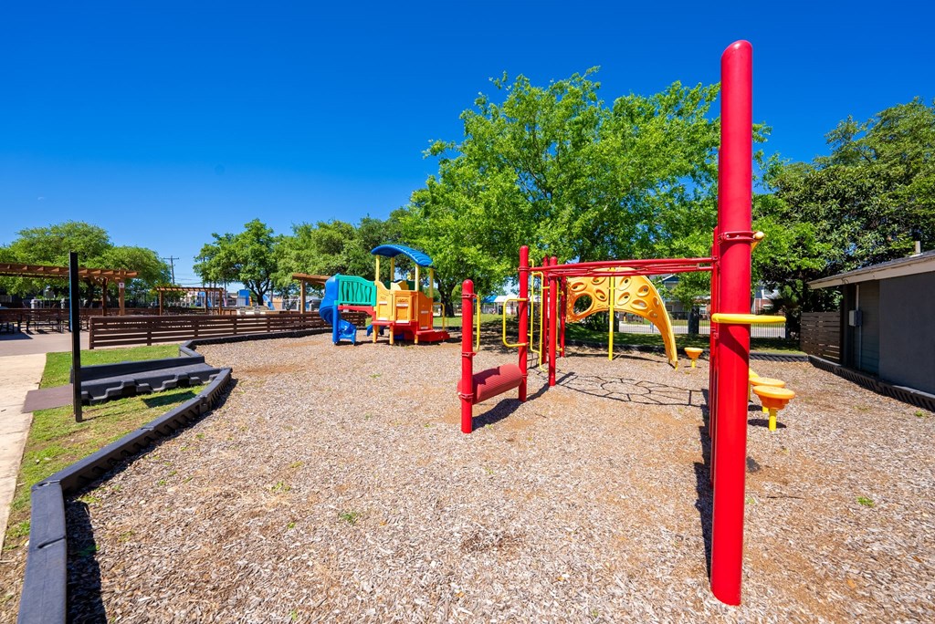 A playground with a red structure and a yellow slide.