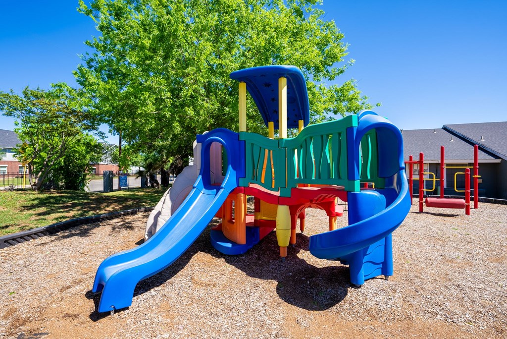 A playground with a blue slide and a green and red structure.