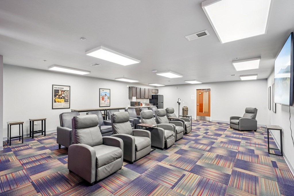 A room with a carpeted floor and a row of chairs.