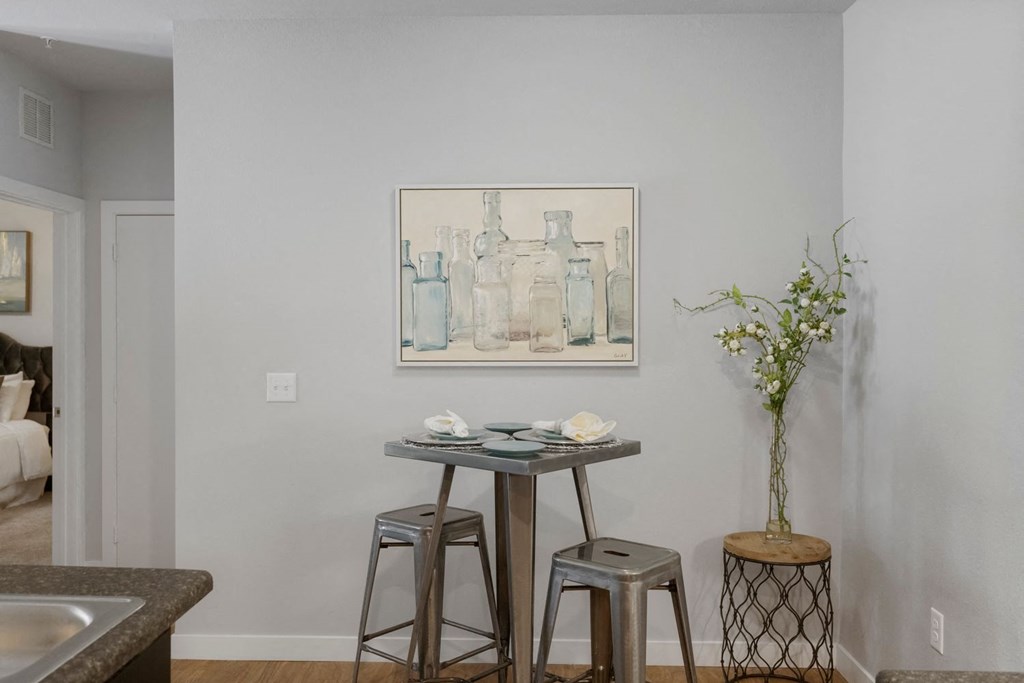 A kitchen with a table and chairs and a painting on the wall.