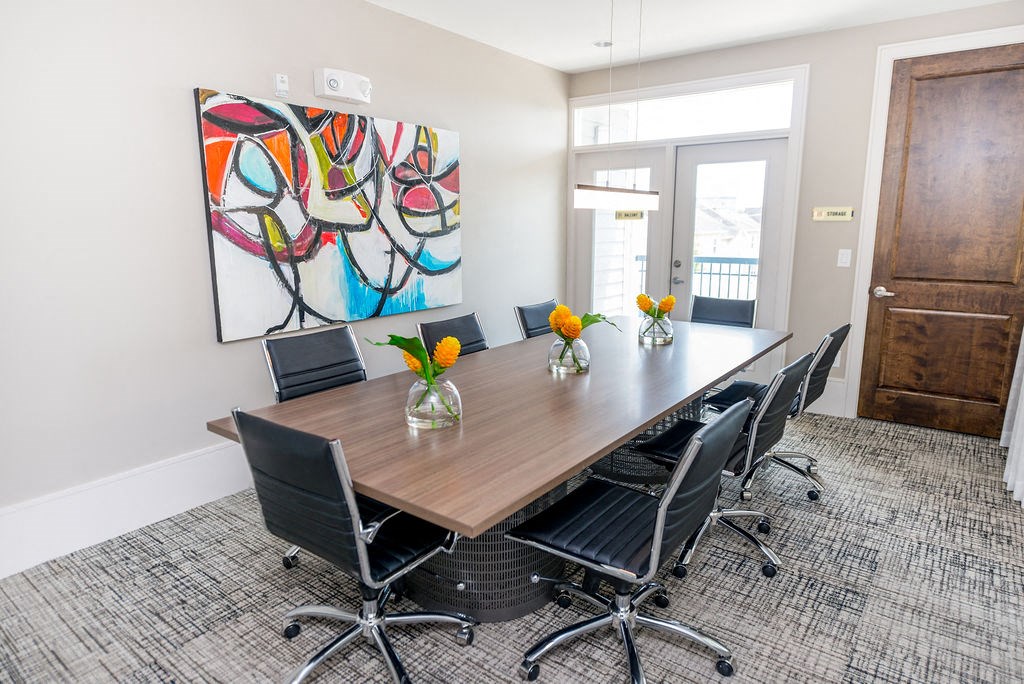 a conference room with a table and chairs and a painting on the wall