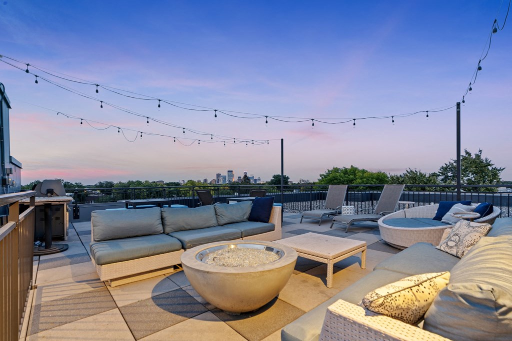 a roof deck with couches and chairs and a fire pit