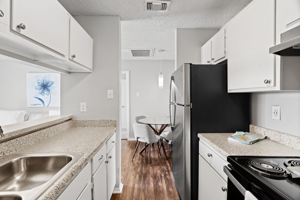 A kitchen with a black refrigerator and white cabinets.