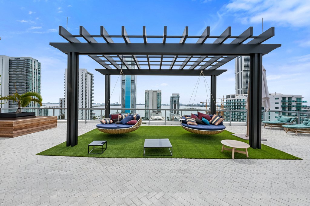 a rooftop lounge area with lounge chairs and a hammock with a view of the city