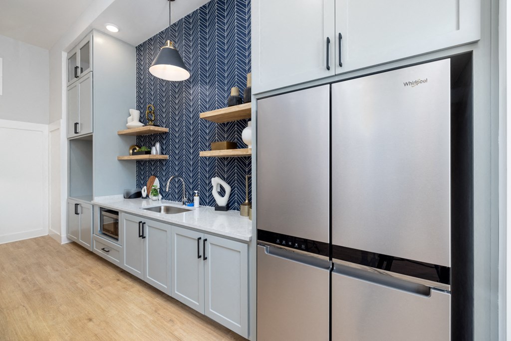 a kitchen with white cabinets and a stainless steel refrigerator and sink