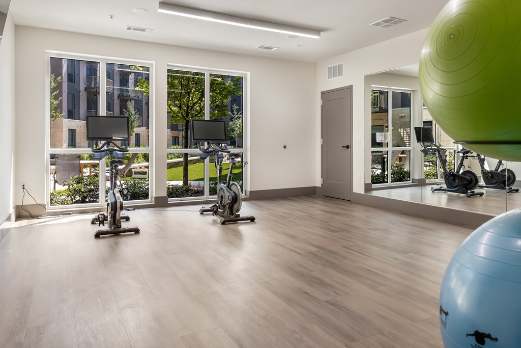 A gym with a green exercise ball and a row of exercise bikes.