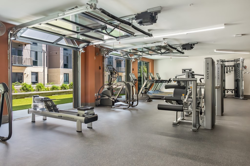 A gym with a variety of equipment including treadmills, weights, and exercise machines.