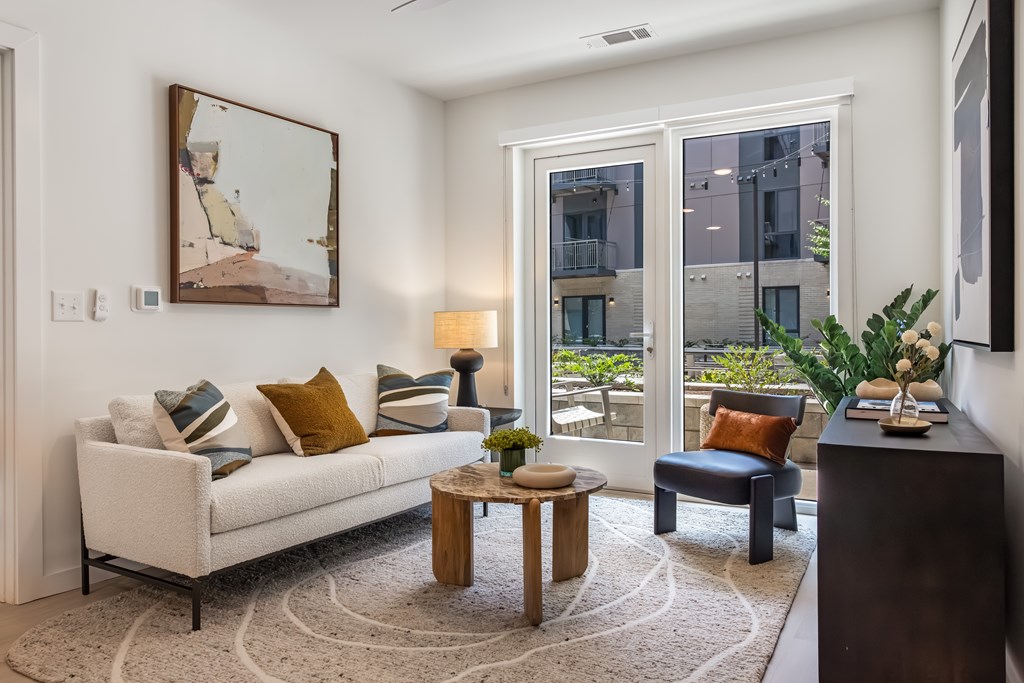 A living room with a white couch, a coffee table, and a painting on the wall.