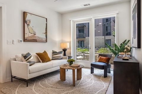 A living room with a white couch, a coffee table, and a painting on the wall.