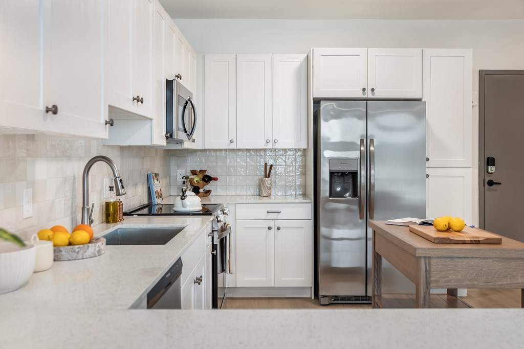 A modern kitchen with white cabinets and a stainless steel refrigerator.