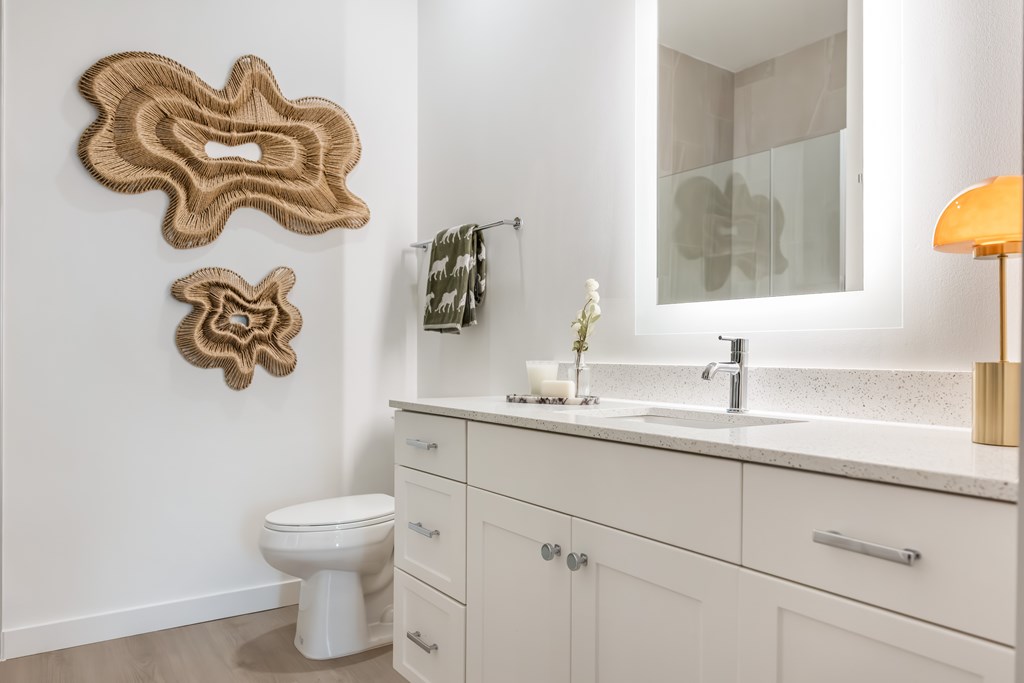A bathroom with a toilet, sink, and mirror.