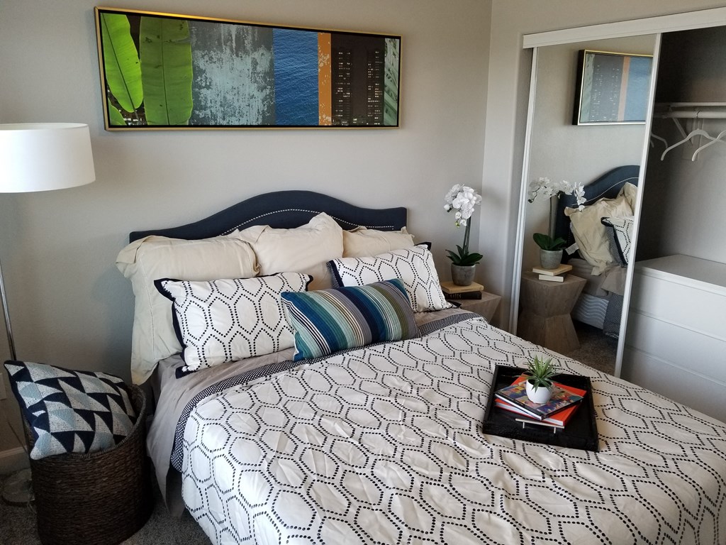 a bedroom with a bed and a nightstand with a plant on it