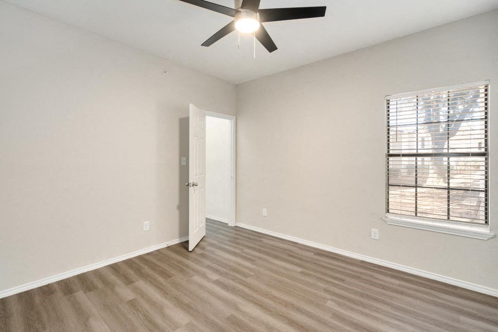an empty living room with a ceiling fan and a window