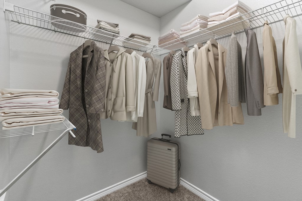 a closet with a rack of clothes and a suitcase