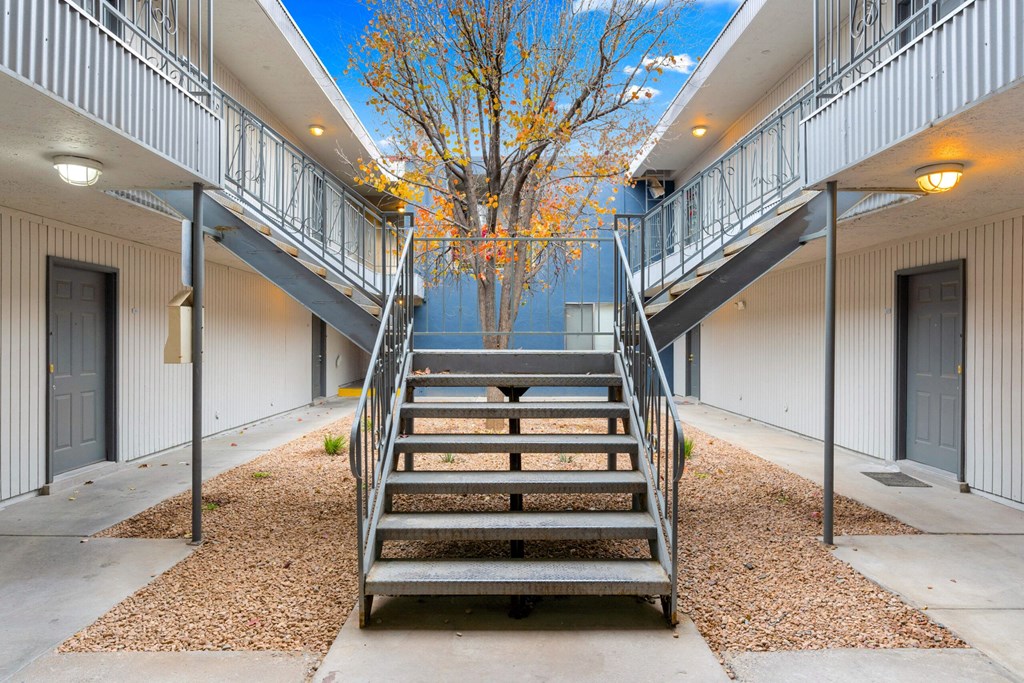 a set of stairs with a tree in the middle between two buildings