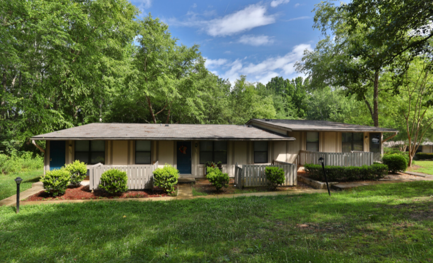 a home with a white picket fence and trees in the background