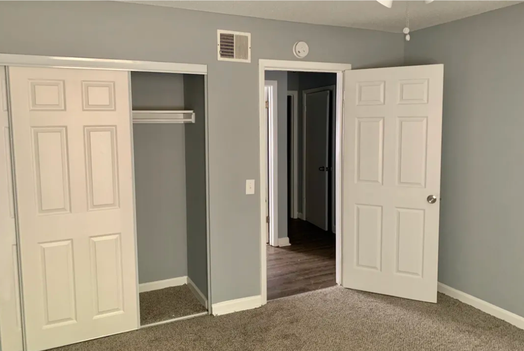 a bedroom with three doors and a door to a closet