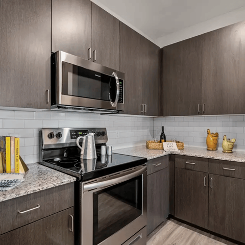 A modern kitchen with dark wood cabinets and stainless steel appliances.