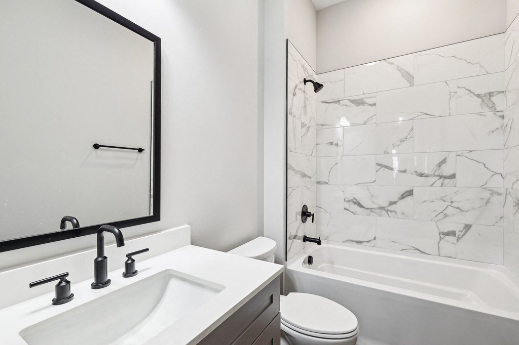 A white sink with a black mirror above it.