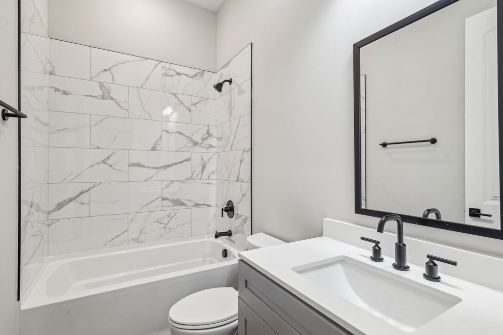 A white bathroom with a marble tile shower.