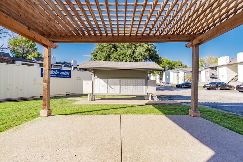 A wooden pergola is over a concrete patio.